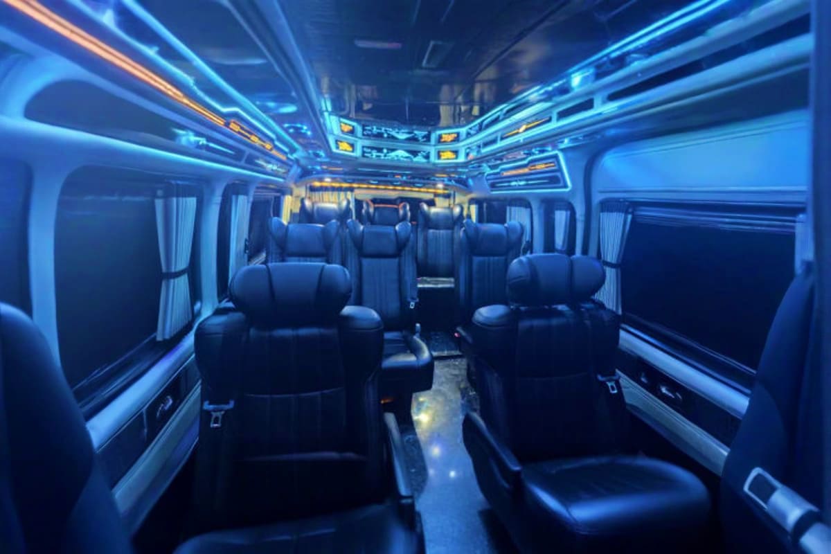 Modern coach bus interior with black leather seats and blue ambient lighting for airport transfer service