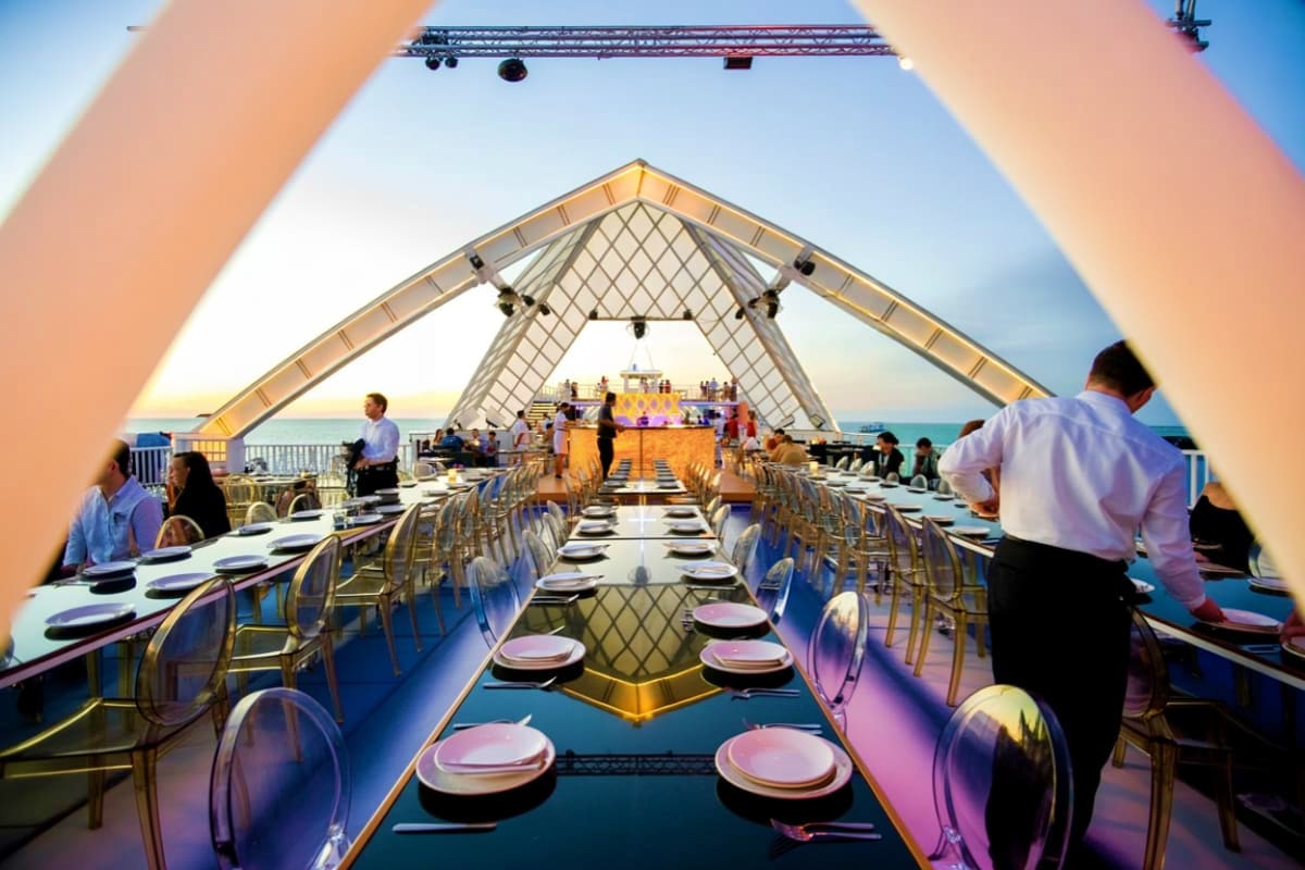 Elegant open-air dining hall on Atlantis Dinner Cruise with long table setup, transparent chairs, place settings, and distinc
