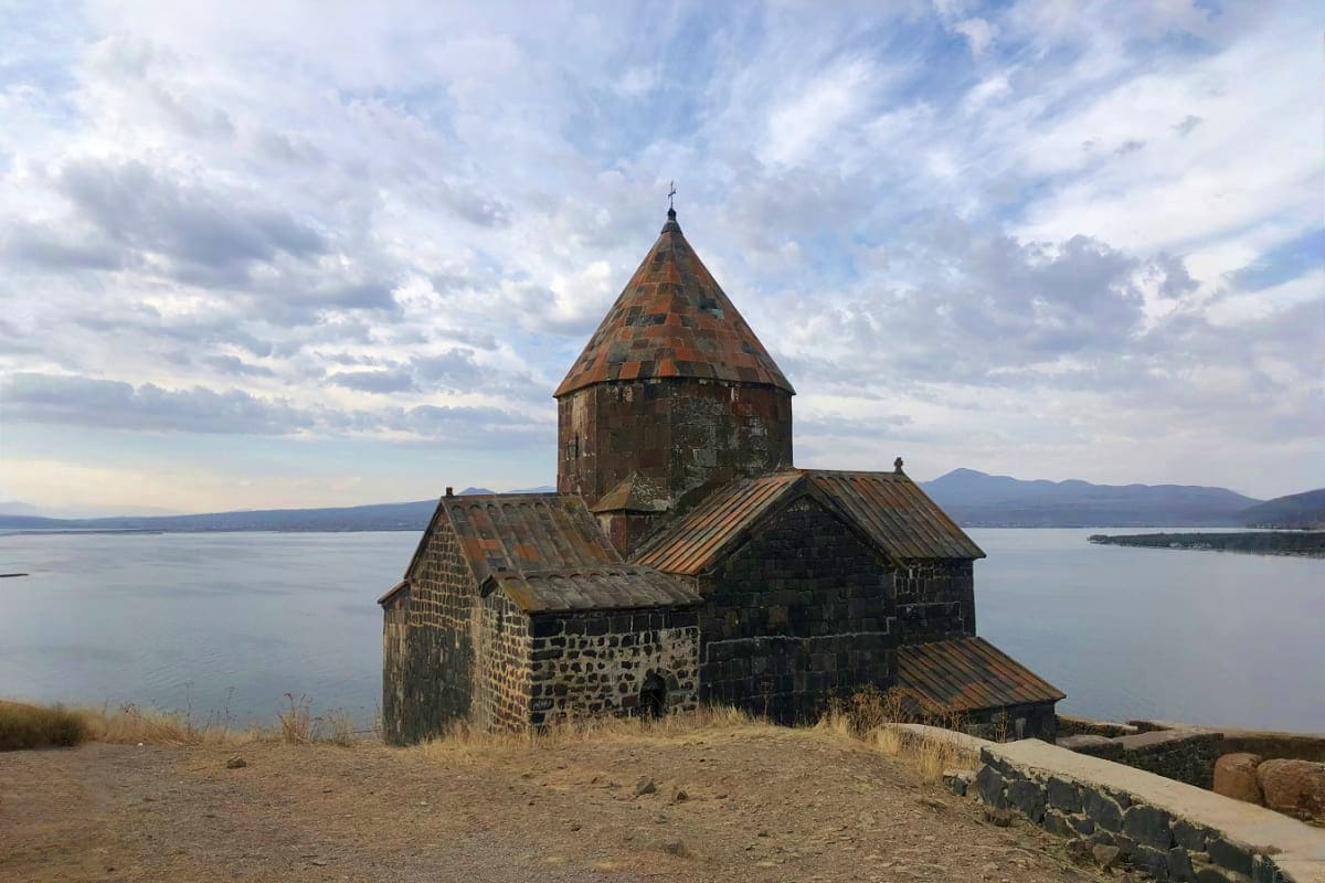 Ancient stone church with conical roof on Lake Sevan shore, Armenia
