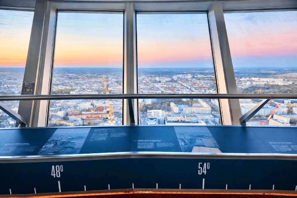 Panoramic view of Frankfurt cityscape at sunset from observation deck with information panel and latitude markers visible thr