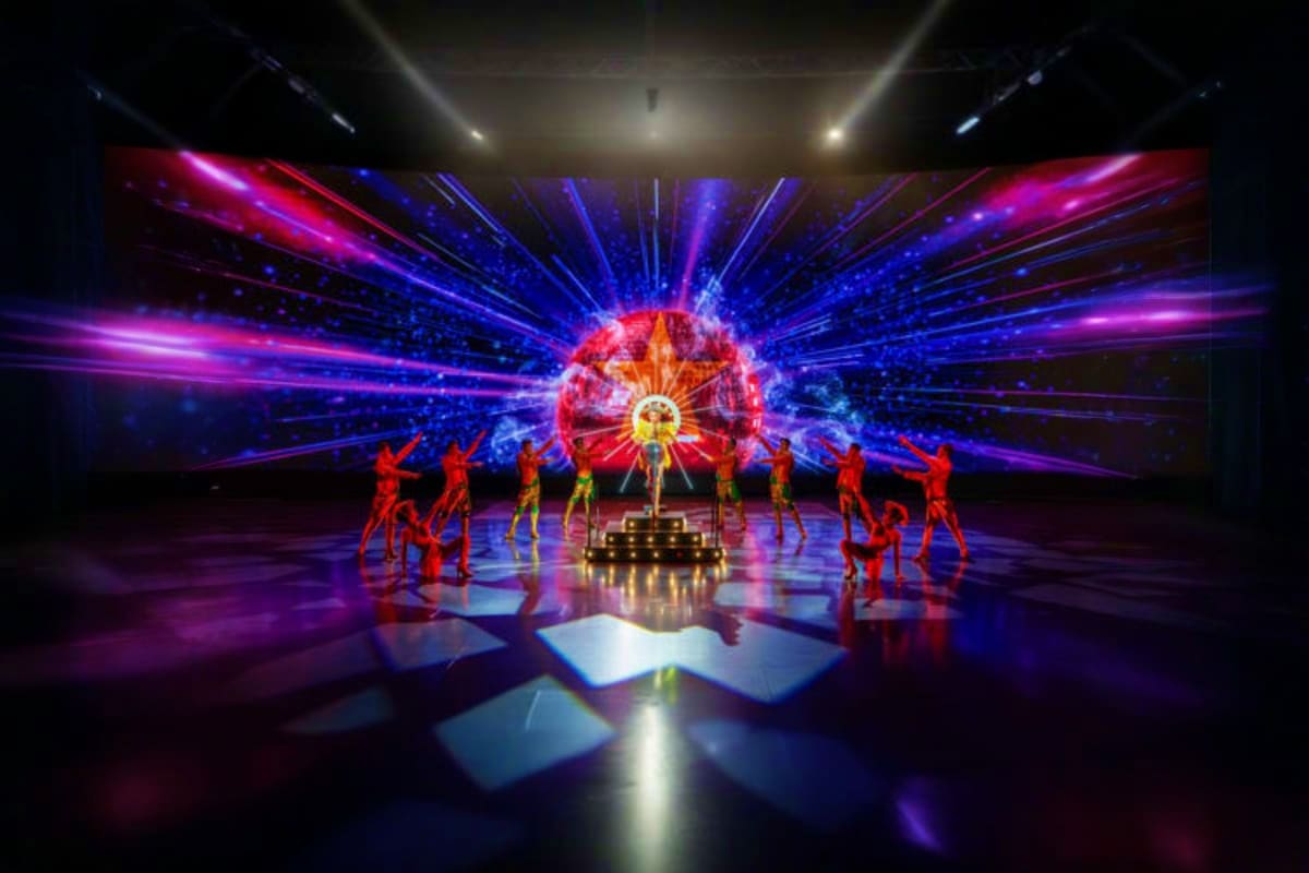 Colosseum Show Pattaya Performers in red outfits dance on stage with vibrant blue and magenta light projections at Colosseum Show Pattaya entertainm