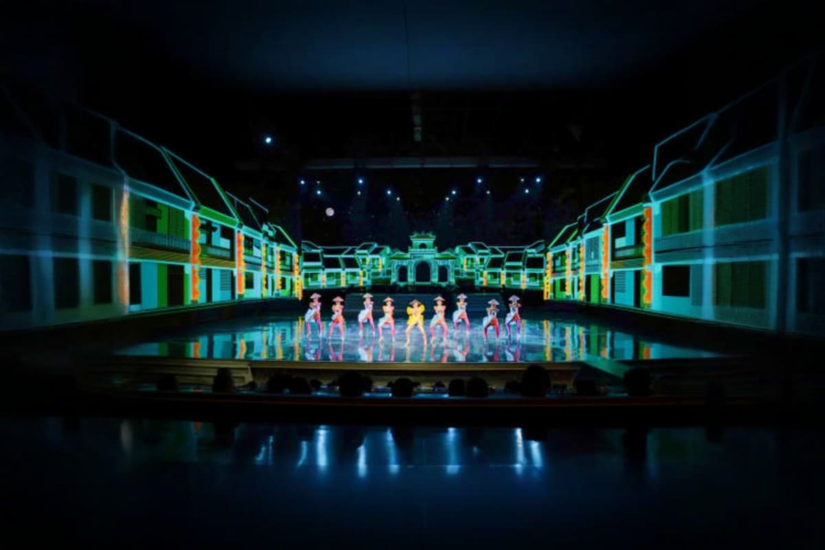 Colosseum Show Pattaya Performers on stage at Colosseum Show Pattaya with illuminated colonial-style building backdrop and reflective water stage fl