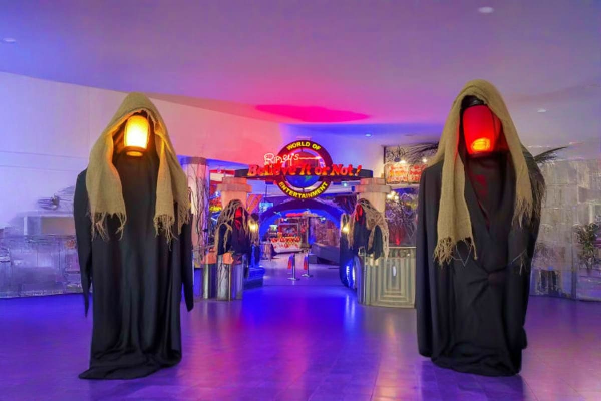 Two ghostly robed figures with glowing eyes flanking entrance to Ripley's Believe It or Not museum with neon signage and purp