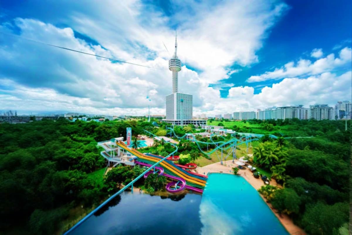 Aerial view of Pattaya Park water park with colorful slides, turquoise pools, and Pattaya City Tower in the background surrou