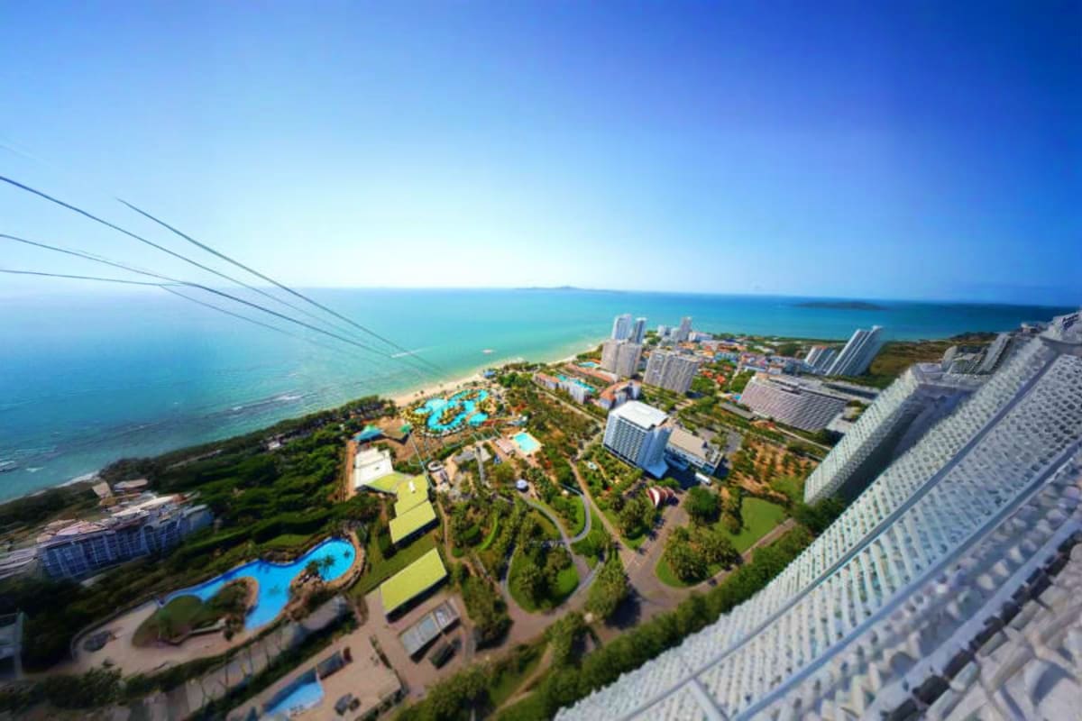Aerial view of Pattaya Park beachfront resort with pools, high-rise hotels, manicured grounds, and turquoise seawater along T