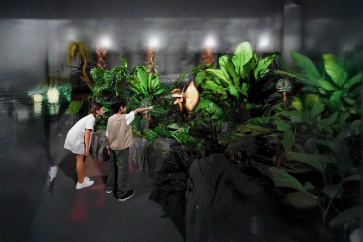 Jurassic World Park Children exploring exotic tropical plants in an indoor greenhouse with overhead lighting and lush green vegetation