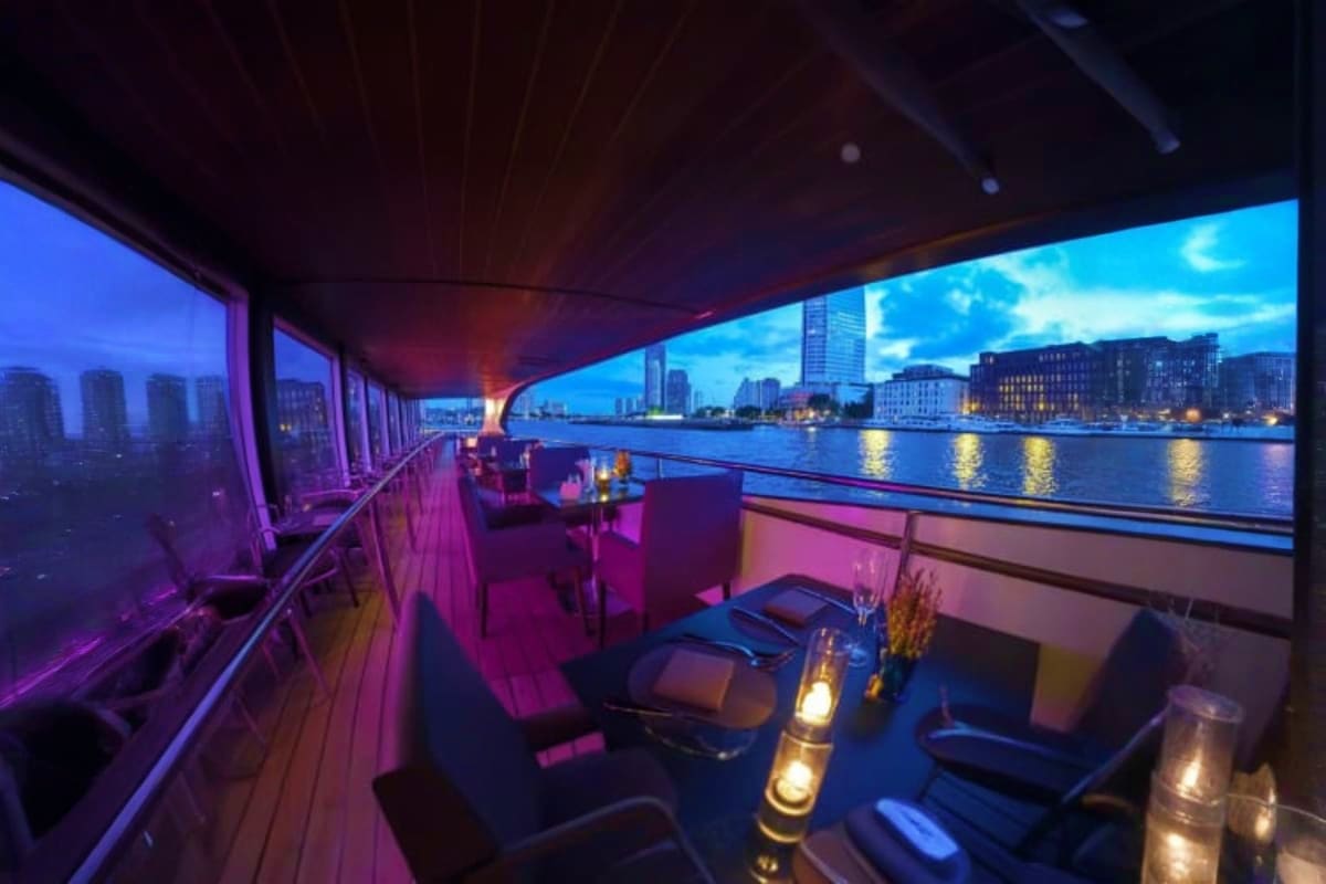 Luxury dining deck on Grand Pearl Cruise with purple ambient lighting, waterfront city skyline, and illuminated harbor views 