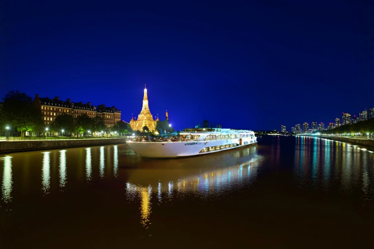 Grand Pearl Cruise River cruise boat illuminated at night with golden pagoda temple and cityscape reflected in water at dusk