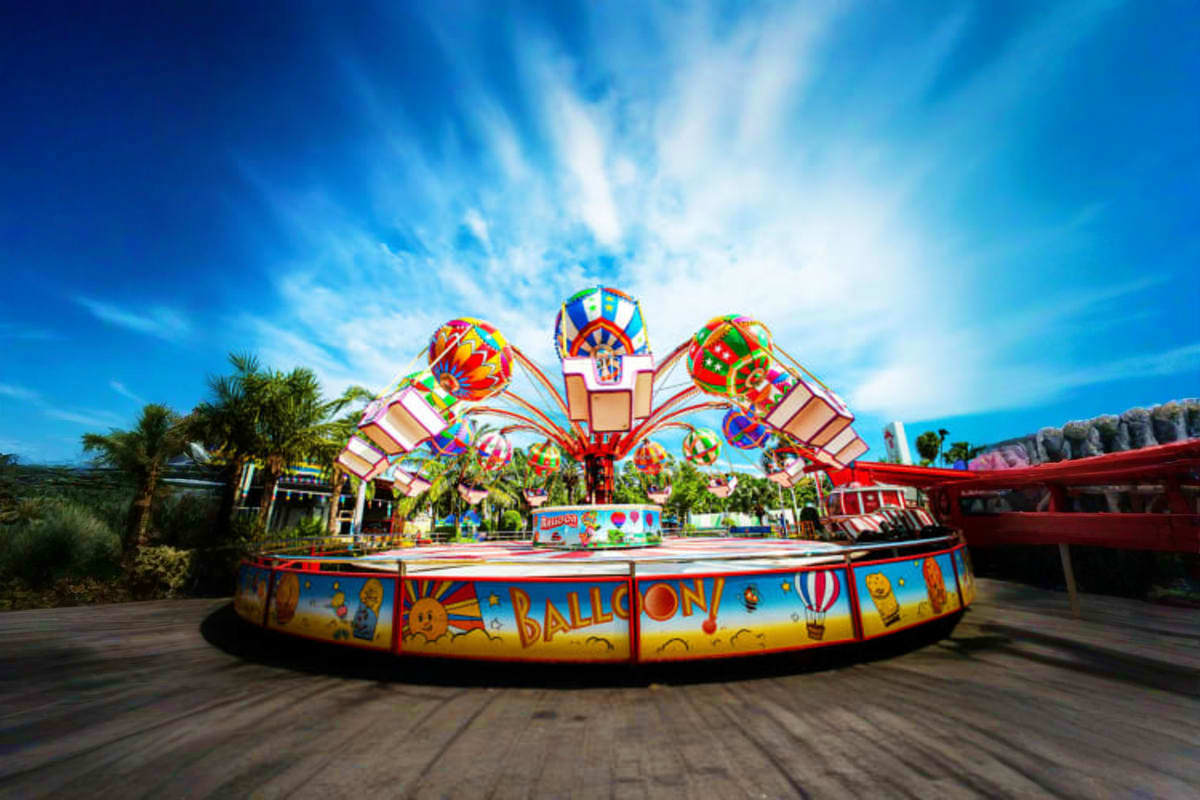 Siam Amazing Park Bangkok Colorful hot air balloon-themed carousel ride at Siam Amazing Park amusement park in Bangkok with blue sky and palm trees