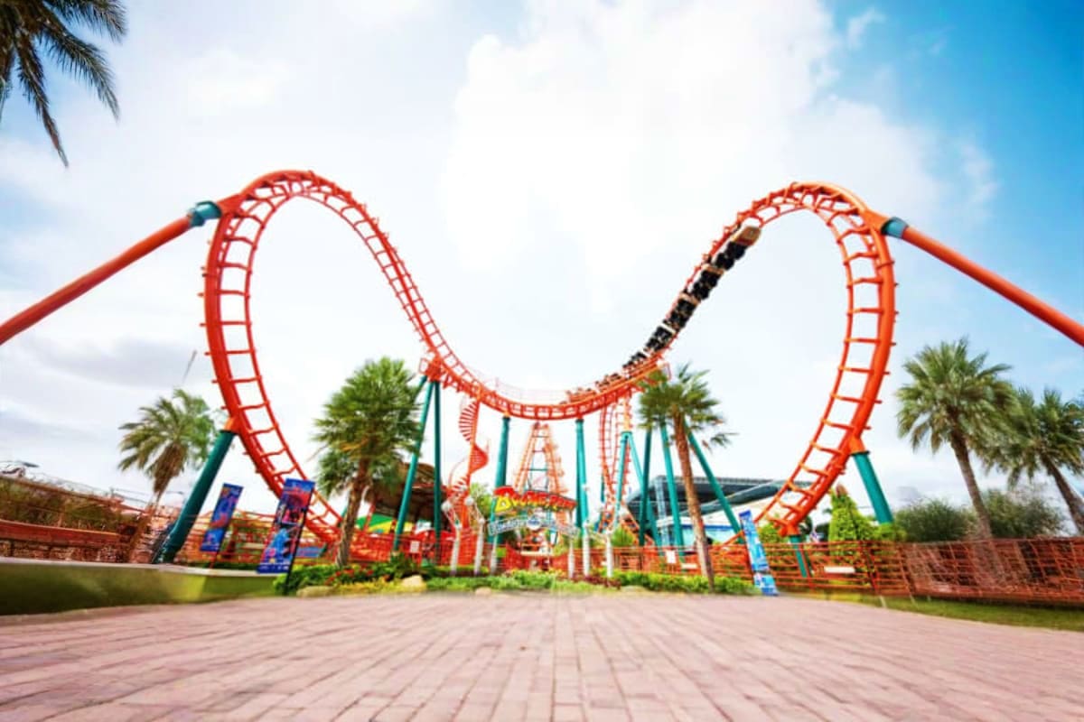 Siam Amazing Park Bangkok Red roller coaster with twin loops at Siam Amazing Park Bangkok, surrounded by palm trees and blue sky