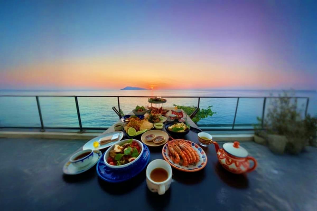 Sunset dinner spread on table overlooking calm ocean with island silhouette at horizon from cruise deck