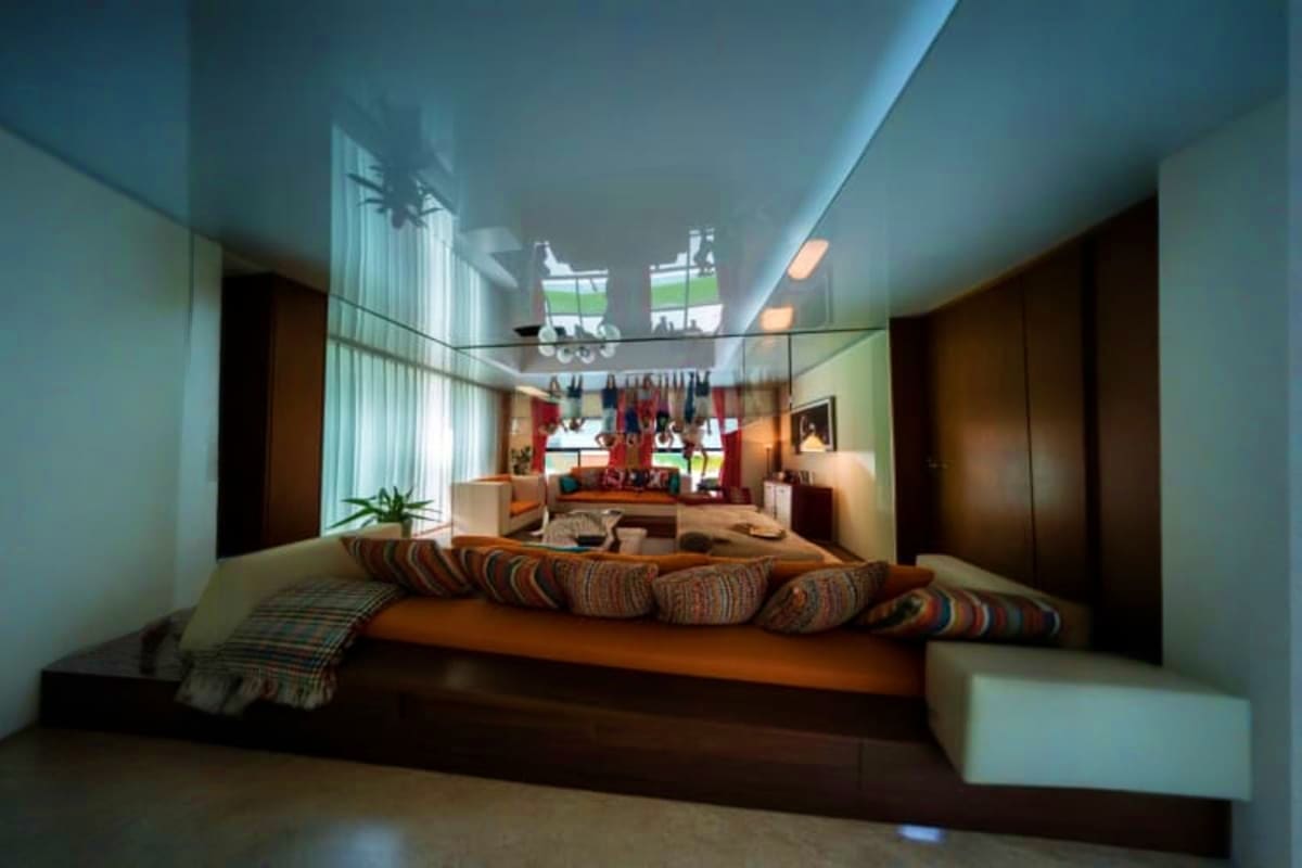 The Upside Down House Museum Modern interior design concept with inverted bedroom platform featuring orange bed frame and striped pillows overlooking lowe