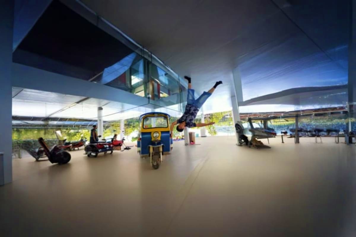 The Upside Down House Museum Person doing acrobatic flip inside modern museum space with blue and yellow auto-rickshaw and inverted furniture exhibits