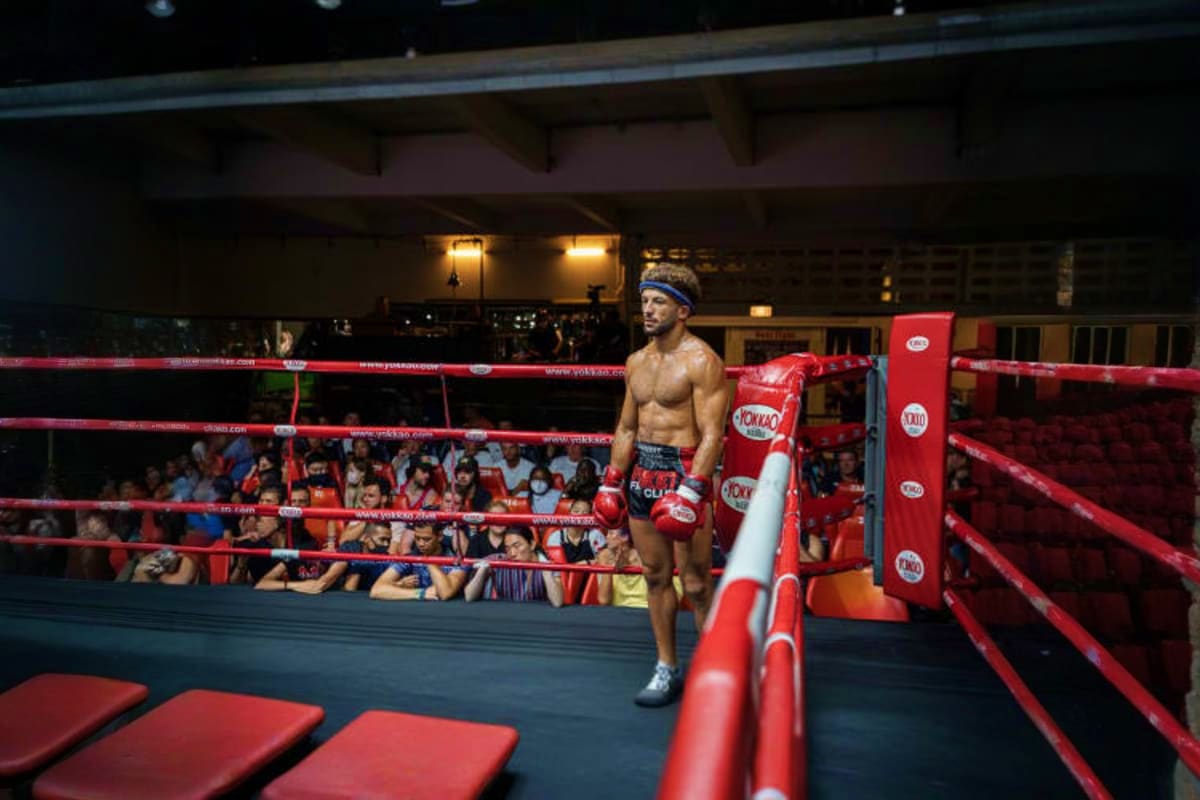 Shirtless boxer standing in red boxing ring at Patong Boxing Stadium with audience seated around the ring