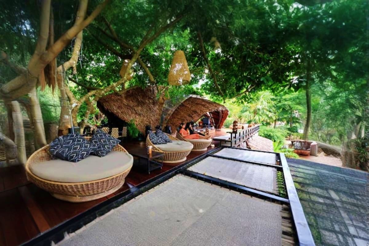 Tropical resort pathway with woven basket seating, thatched roof structures, and lush green trees at Hanuman world