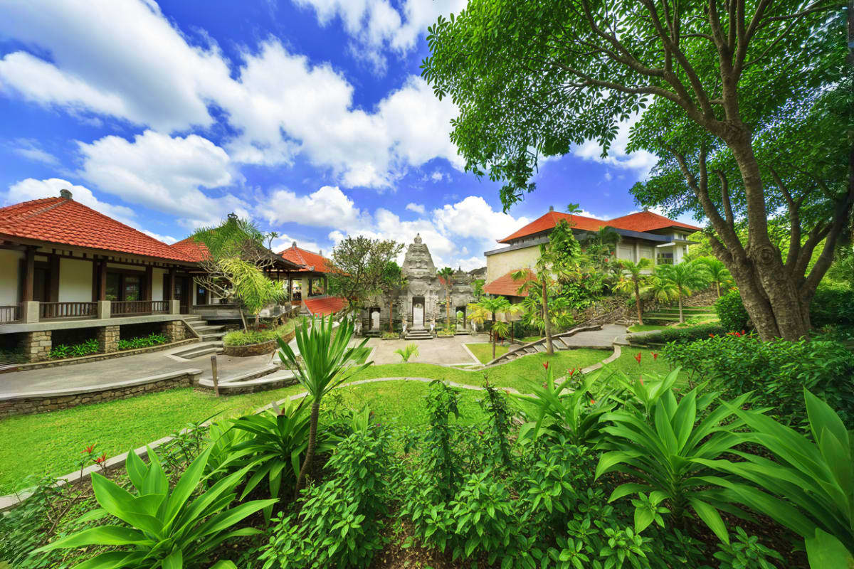 Museum Puri Lukisan courtyard with traditional Balinese architecture, stone temple, lush gardens, and tropical plants under b