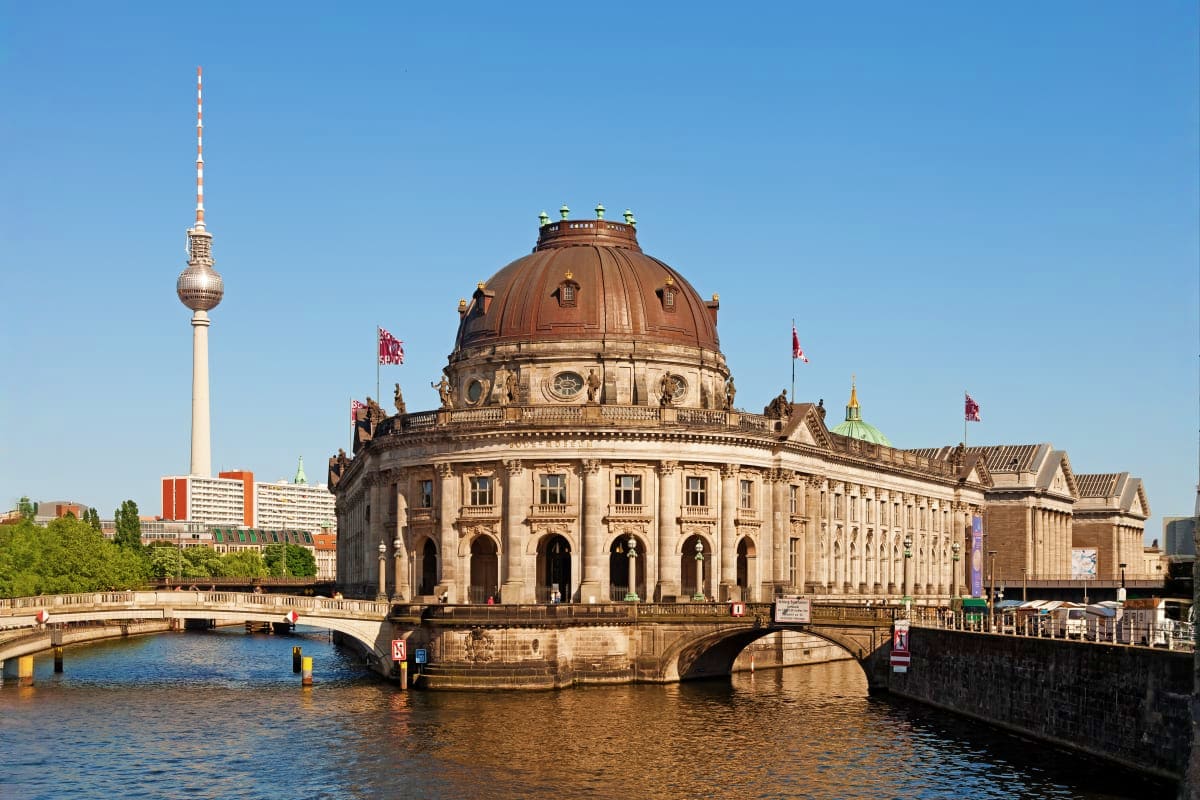 Bode Museum on Museum Island in Berlin with Spree River, bridge, and TV Tower in background on clear day