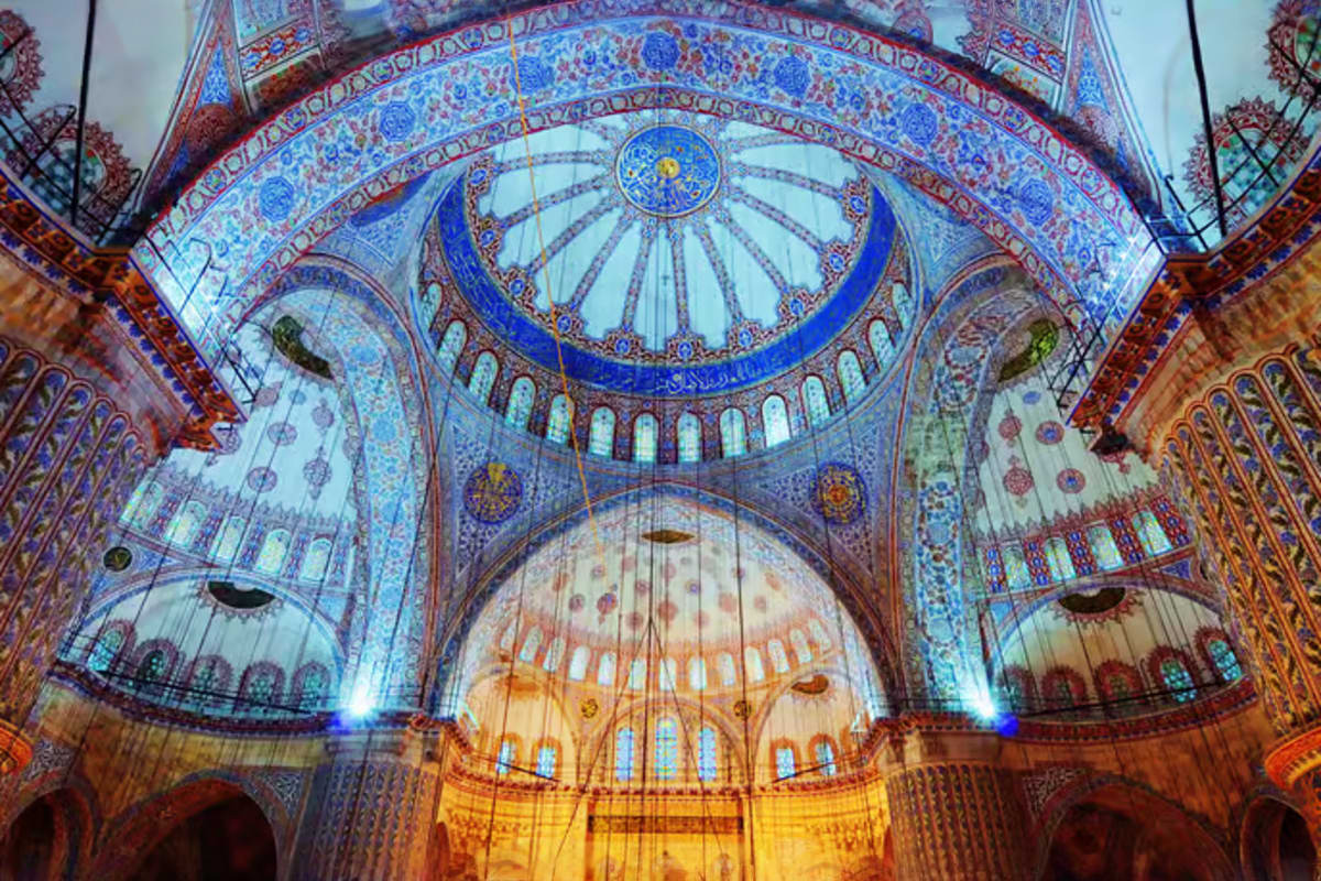 Interior of Blue Mosque in Istanbul showing ornate blue tilework, domed ceiling with geometric patterns, and arched windows w