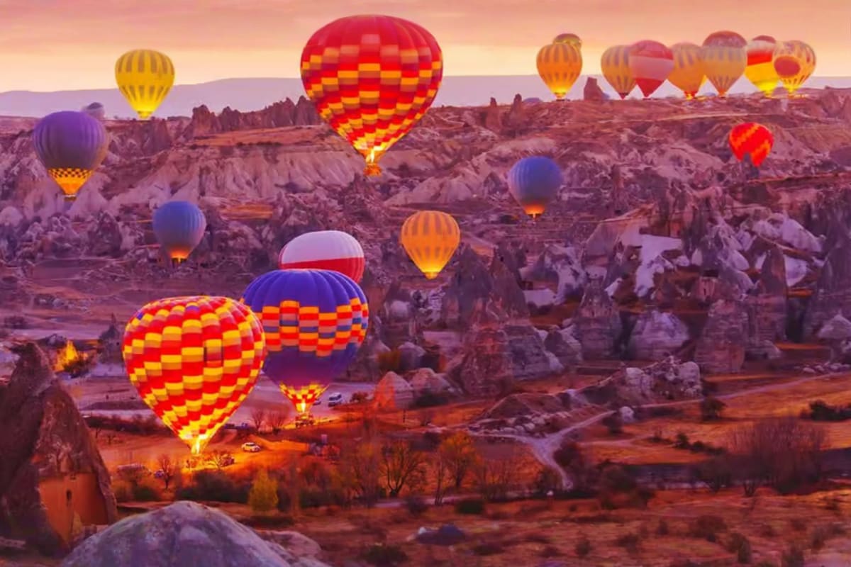 Multiple colorful hot air balloons floating above the fairy chimneys and rock formations of Cappadocia at sunrise
