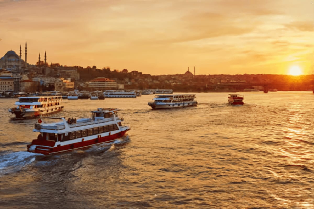 Golden sunset over Istanbul's Bosphorus Strait with traditional red and white ferries anchored in the water and mosques with 