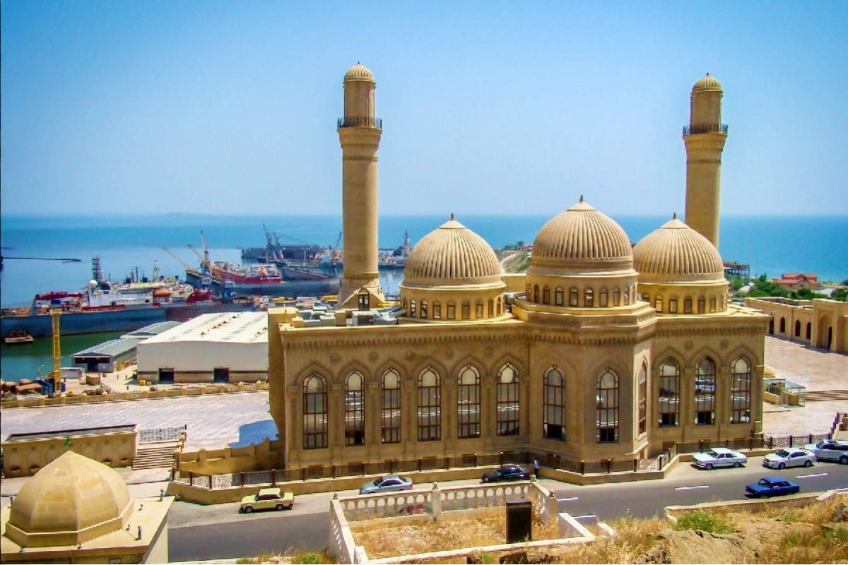 Historic mosque with golden domes and minaret overlooking Baku harbor and Caspian Sea
