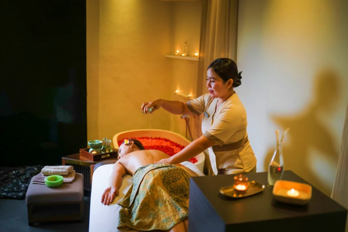 Spa therapist performing a massage treatment on a client in a warm, candlelit treatment room at Jasmine Aromatic House spa in