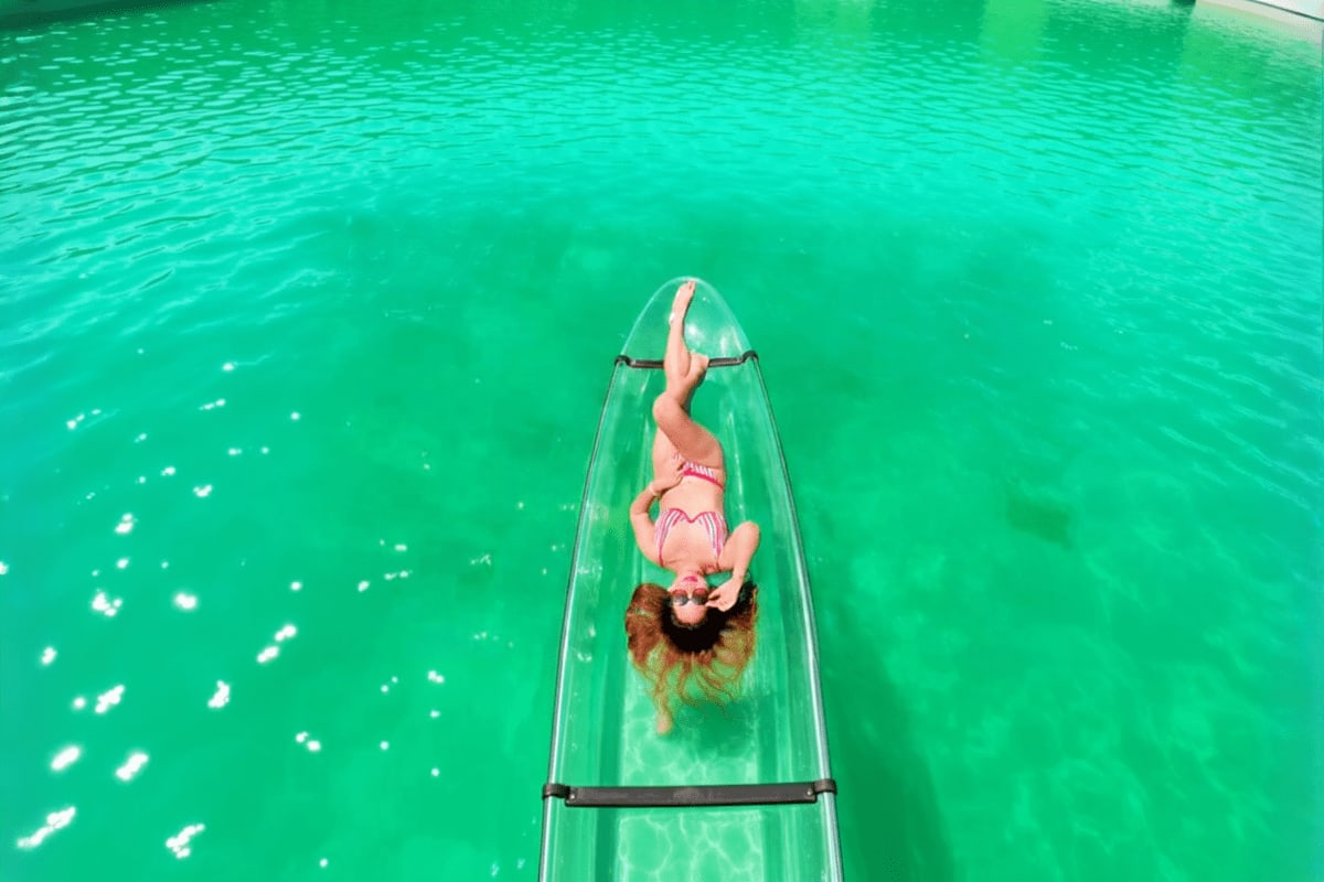 Woman lying on clear bottom kayak in turquoise water, aerial view of Boracay crystal kayak experience
