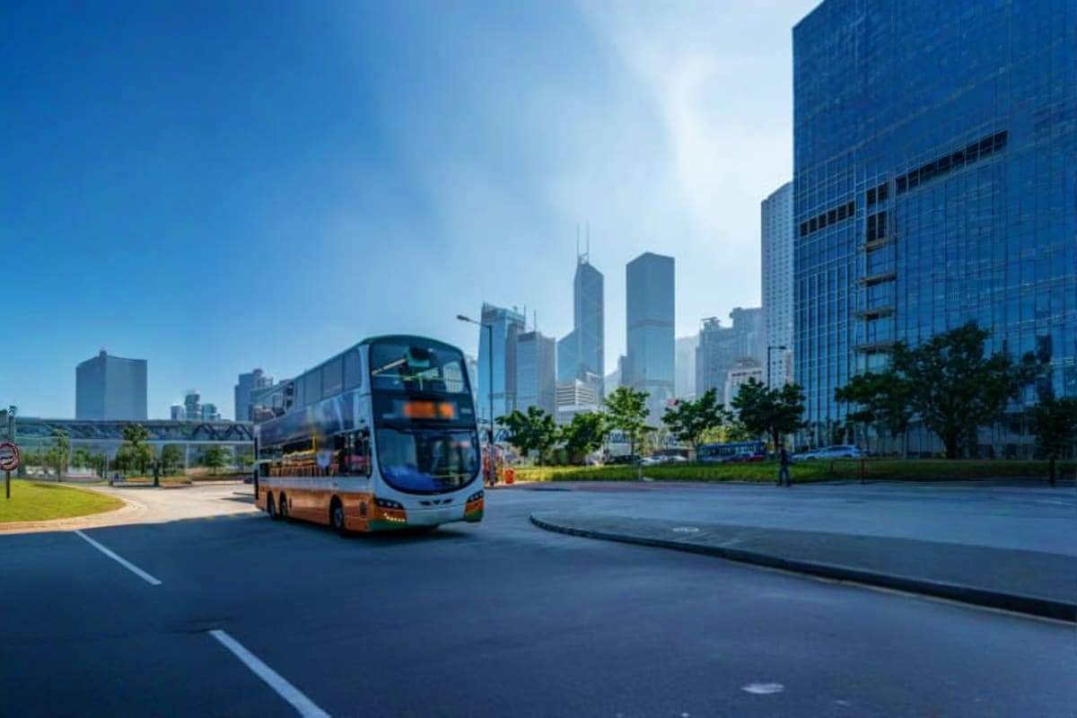 Double-decker tour bus in front of modern Chicago skyline skyscrapers on sunny day