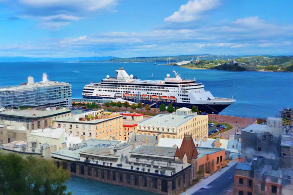 Large cruise ship docked at port with colorful historic buildings and blue water visible in coastal city harbor