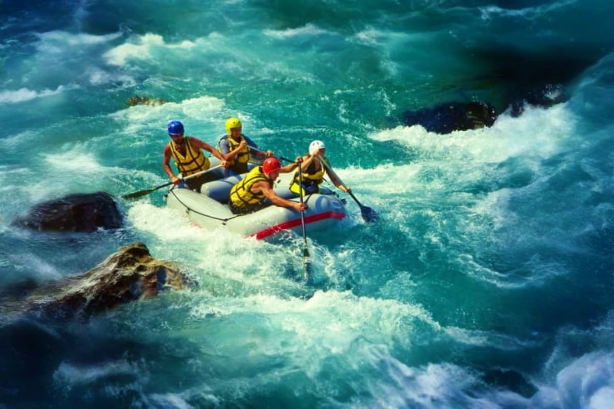 White Water Rafting Group of five people white water rafting in turbulent turquoise river with white rapids and rocky outcrops, wearing yellow an
