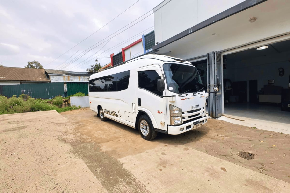 White Isuzu minibus parked at garage entrance for airport transfer service