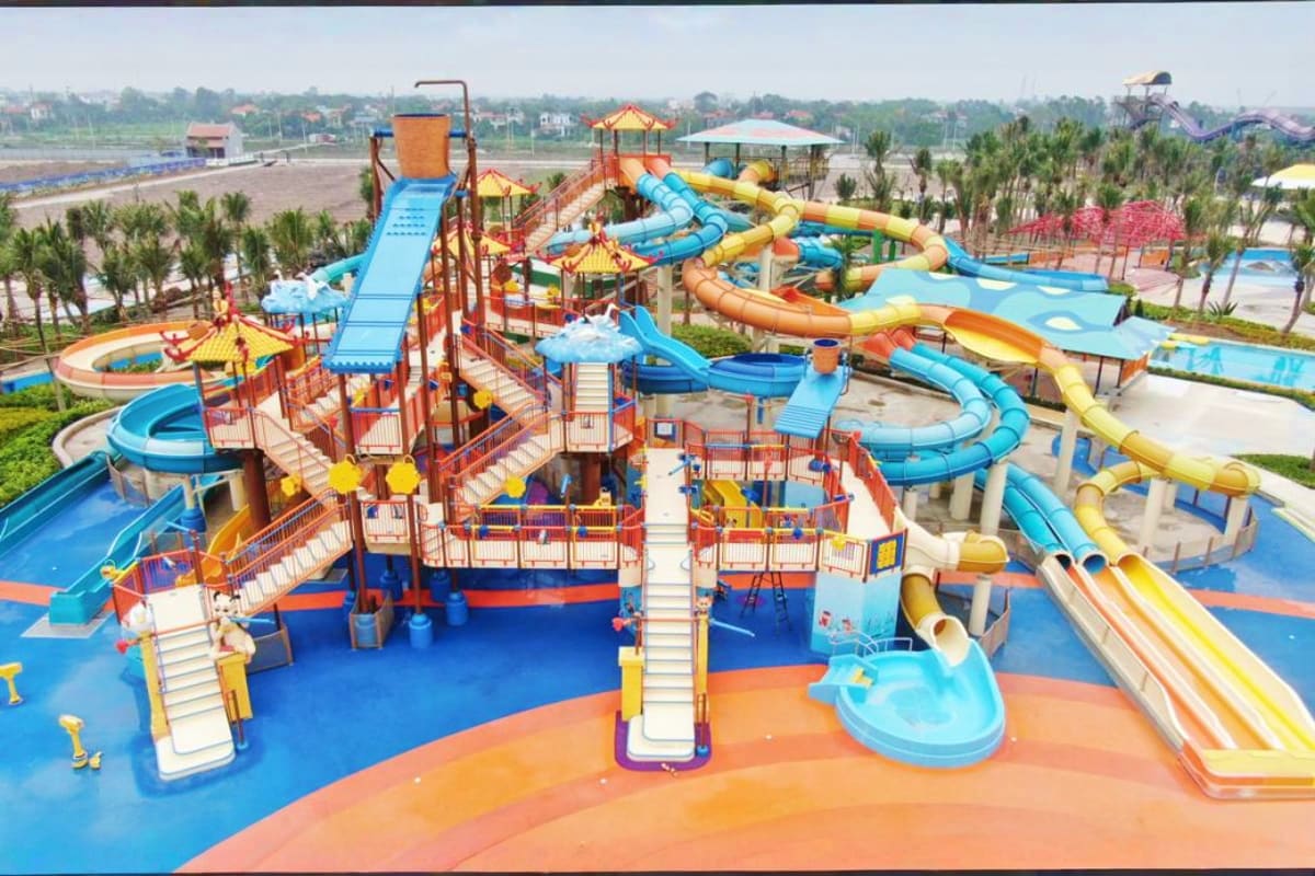 Aerial view of Sun World Ha Nam water park with colorful slides, lazy river, and central tower attraction surrounded by palm 
