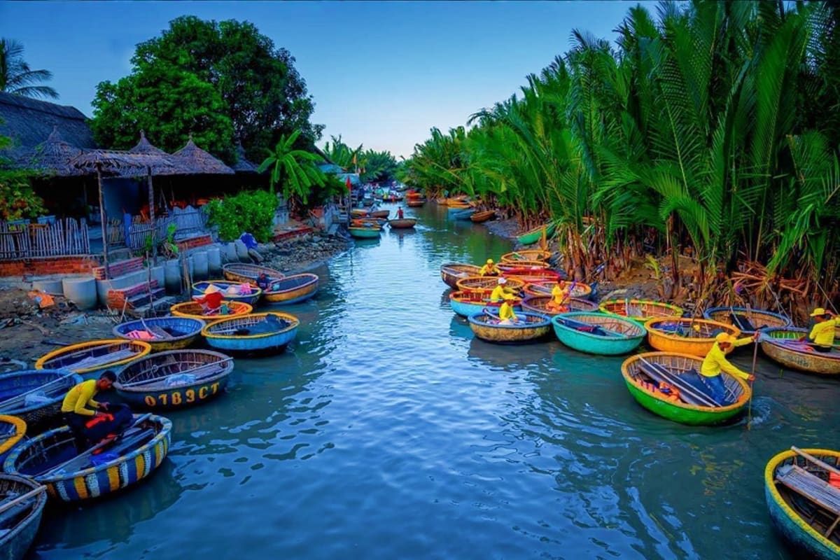 Colorful fishing boats lined in narrow canal with palm trees and traditional thatched-roof shelters in Vietnamese village
