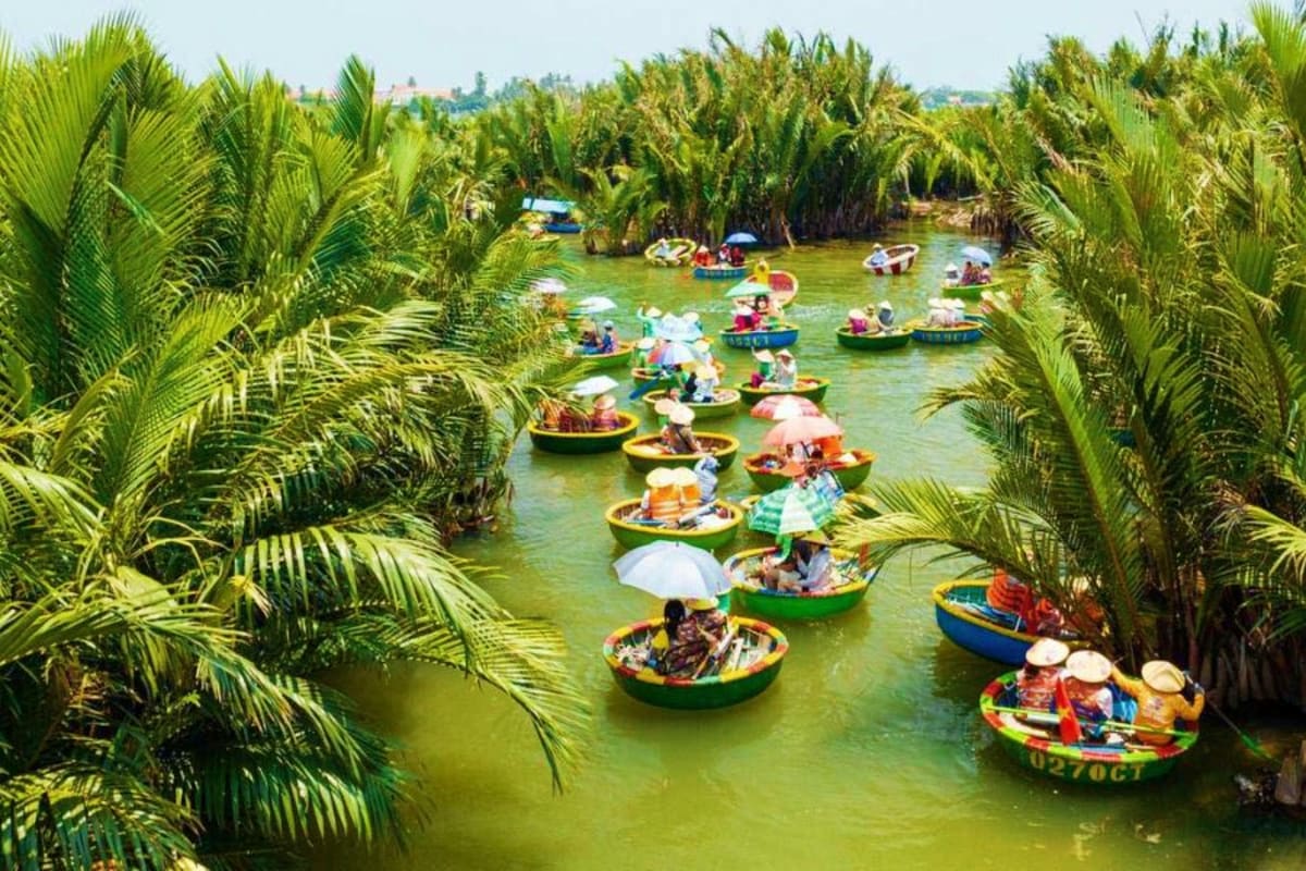Colorful boats filled with tourists navigating through a narrow waterway surrounded by dense green palm trees in a tropical c