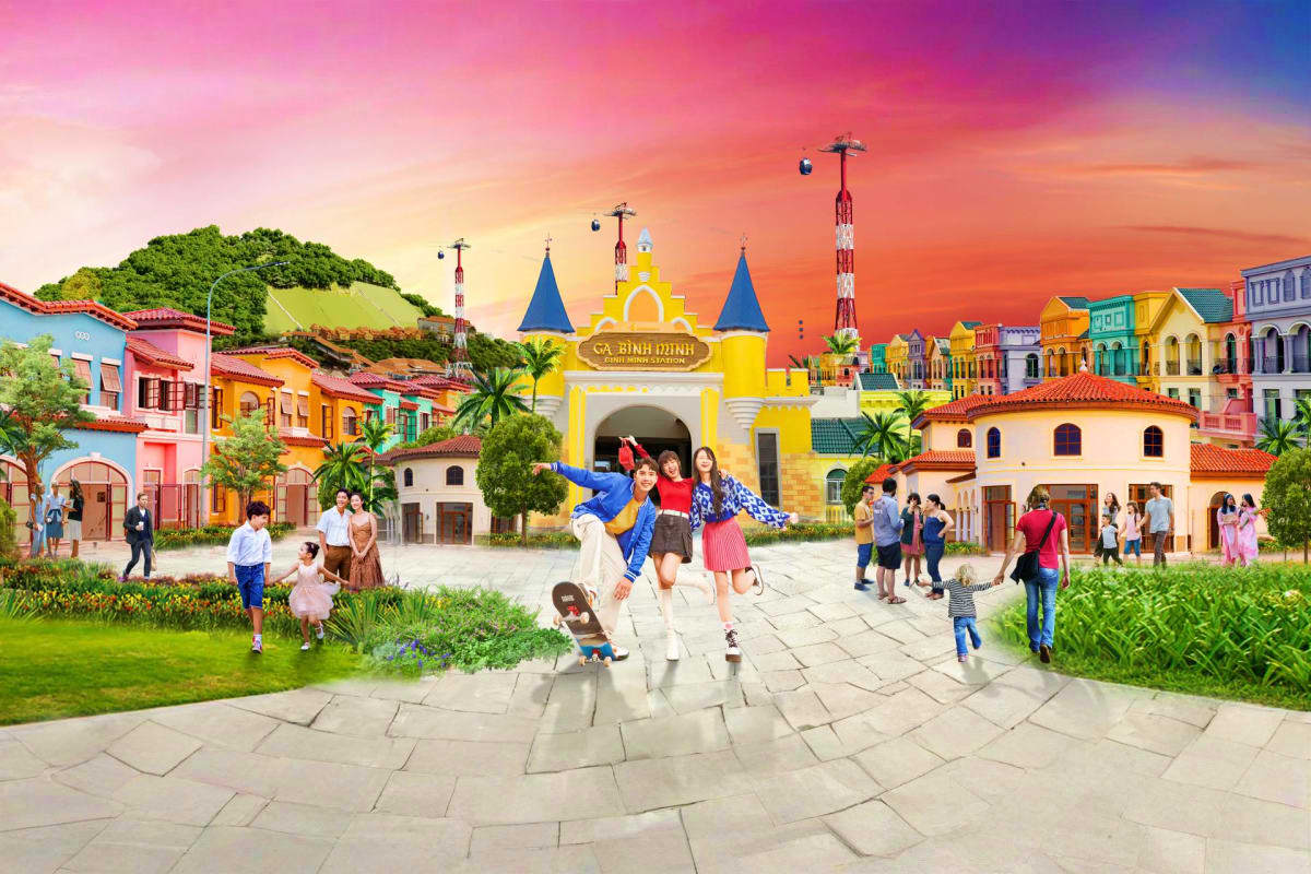 Colorful colonial-style buildings and yellow castle entrance at Vinwonders Cua Hoi theme park with visitors enjoying the plaz