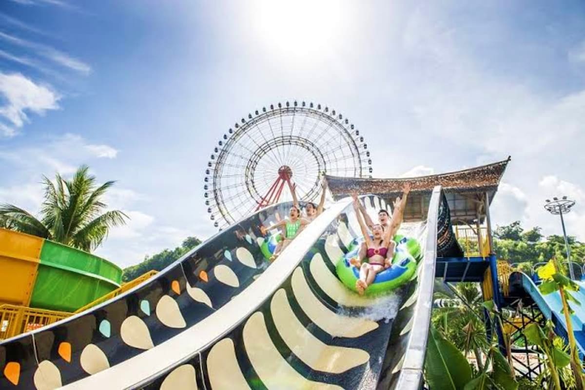 Water slide at Vinwonders Cua Hoi amusement park with Ferris wheel visible in background and tropical palm trees