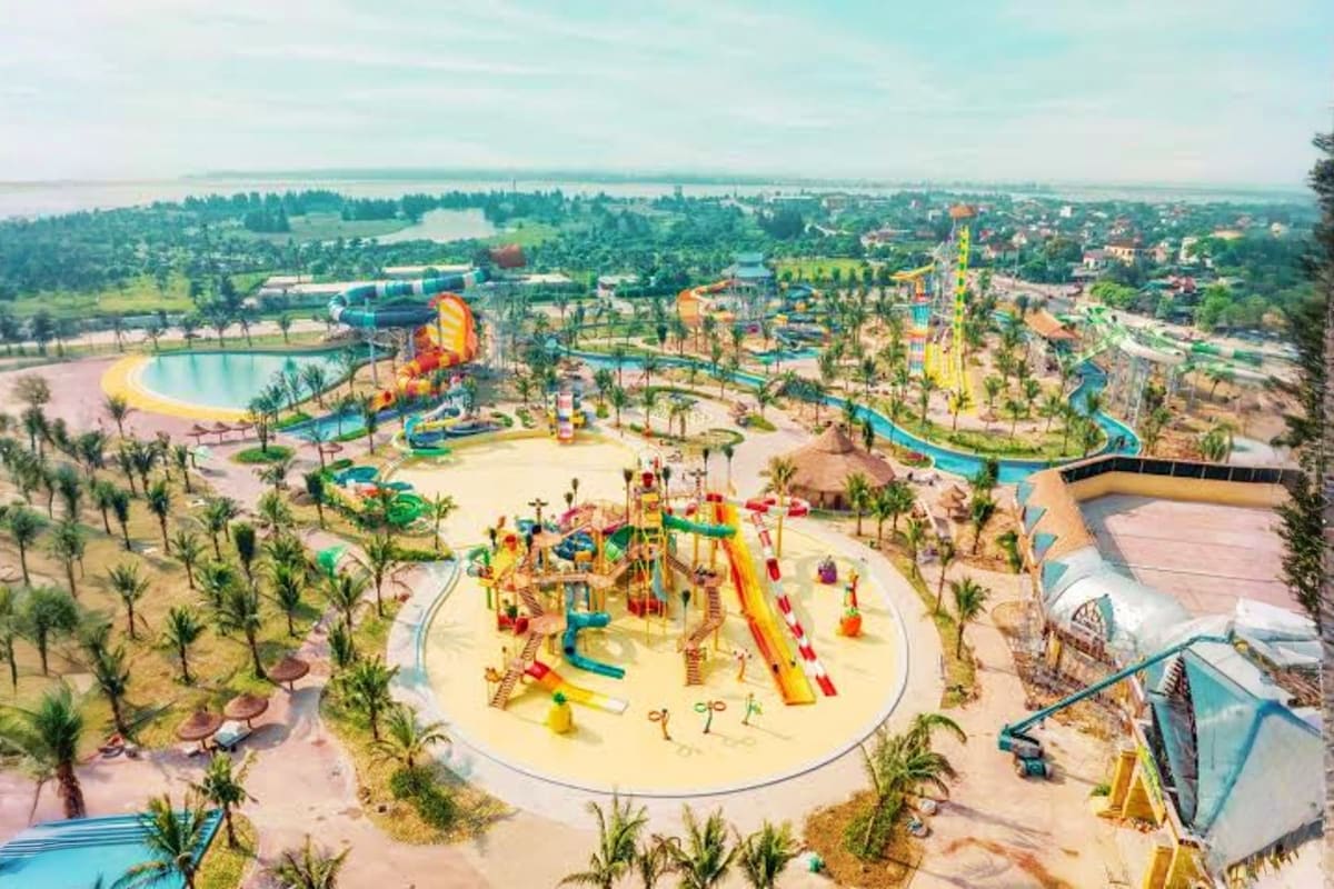 Aerial view of Vinwonders Cua Hoi water park with colorful slides, pools, palm trees, and surrounding landscape