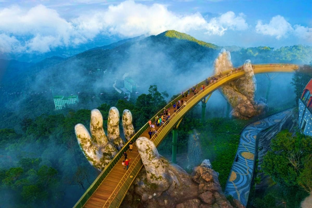 Golden Bridge held by giant stone hands with tourists walking across misty mountains in Danang, Vietnam