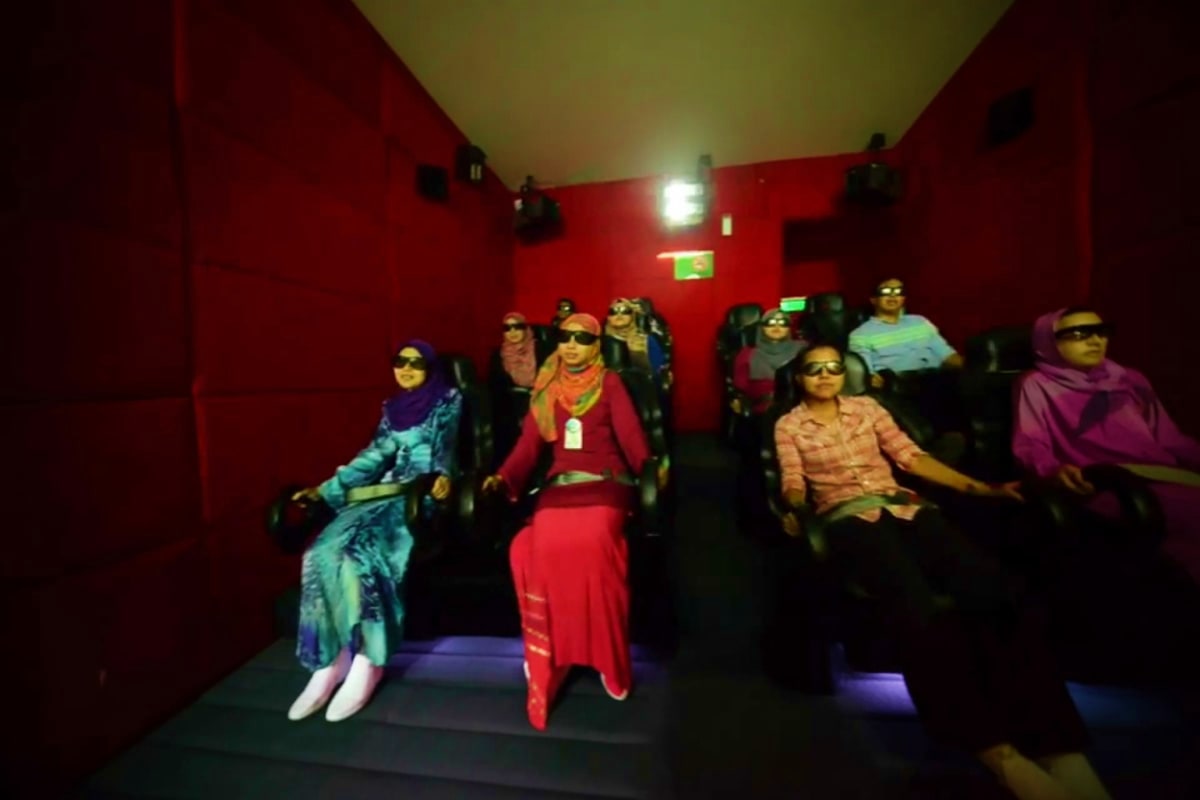 Audience wearing 3D glasses sitting in red-walled cinema theater during Cinemotion 4D motion ride experience at Panorama Lang