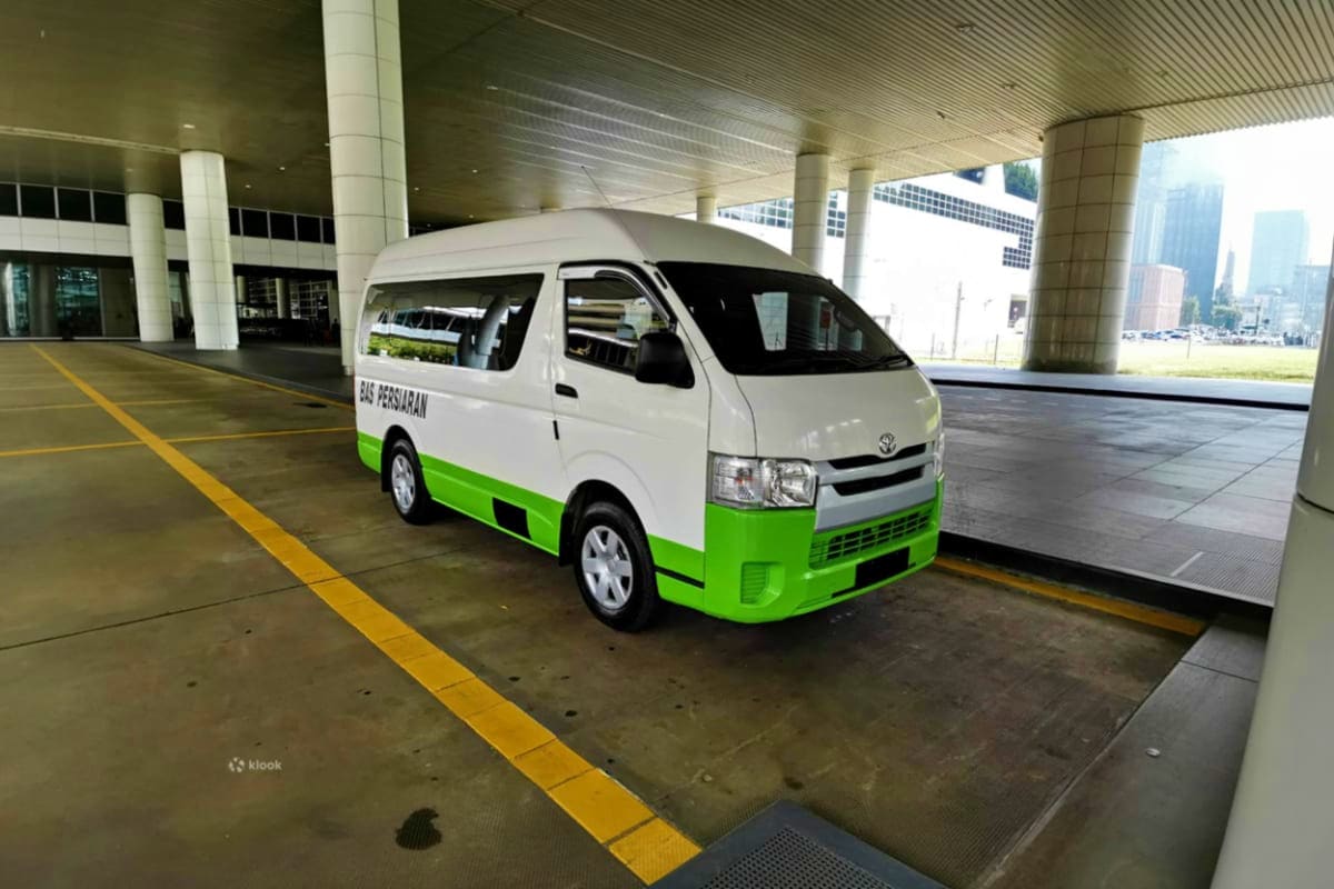 White and green Toyota minivan parked under covered airport departure area with yellow lane markings