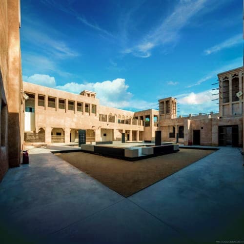 Modern courtyard of Al Shindagha Museum with traditional Arabic architecture, blue sky, and central water feature