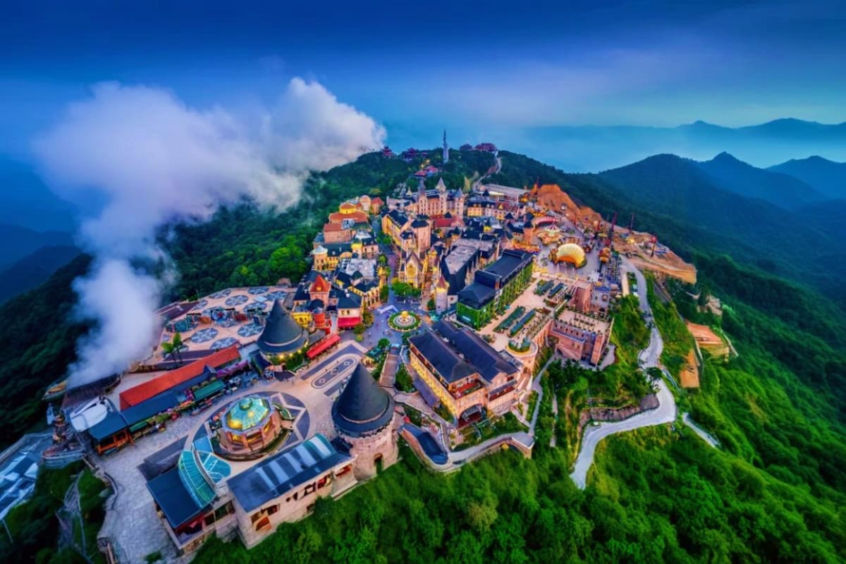 Aerial view of Bana Hills theme park nestled on a misty mountain in Vietnam, featuring colorful buildings, attractions, and a