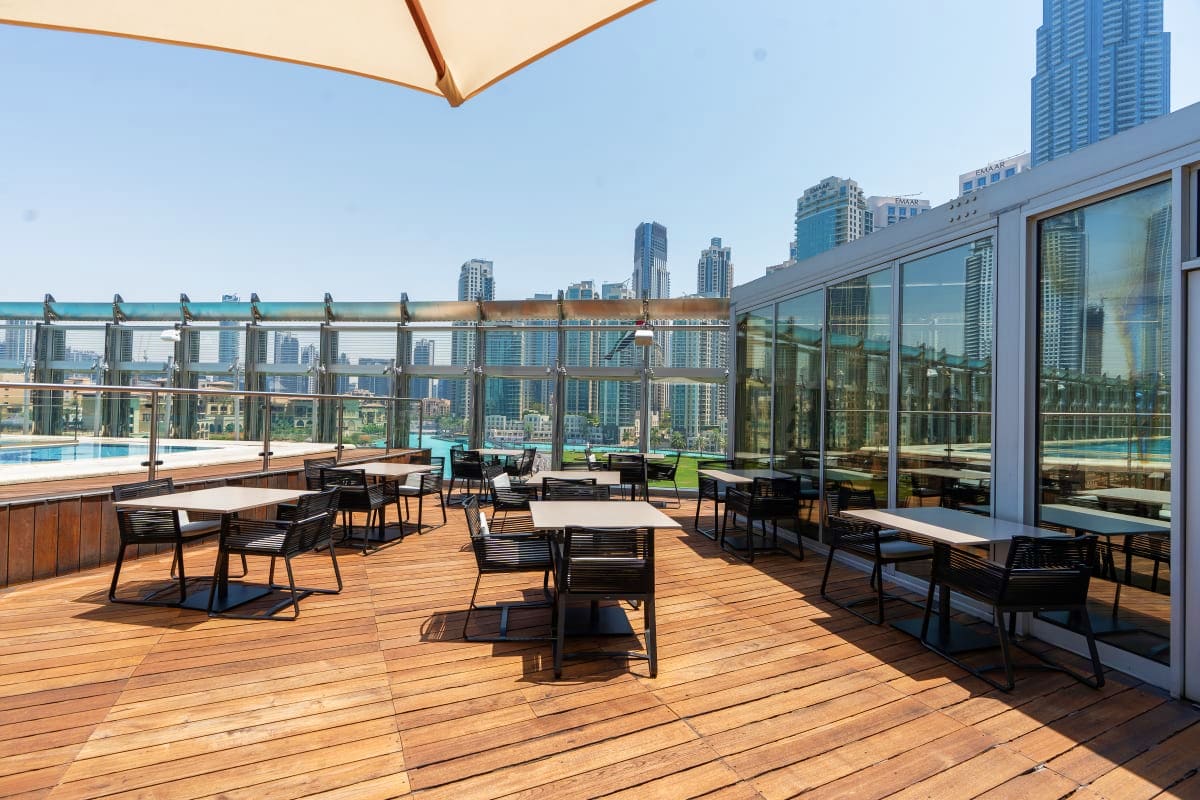 Rooftop terrace with dining tables overlooking downtown skyline and Burj Khalifa with city views