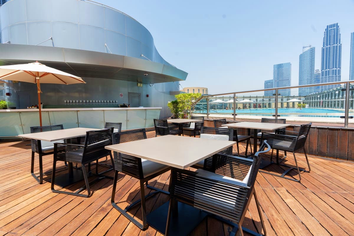 Rooftop dining area with modern seating overlooking Dubai skyline and swimming pool near Burj Khalifa