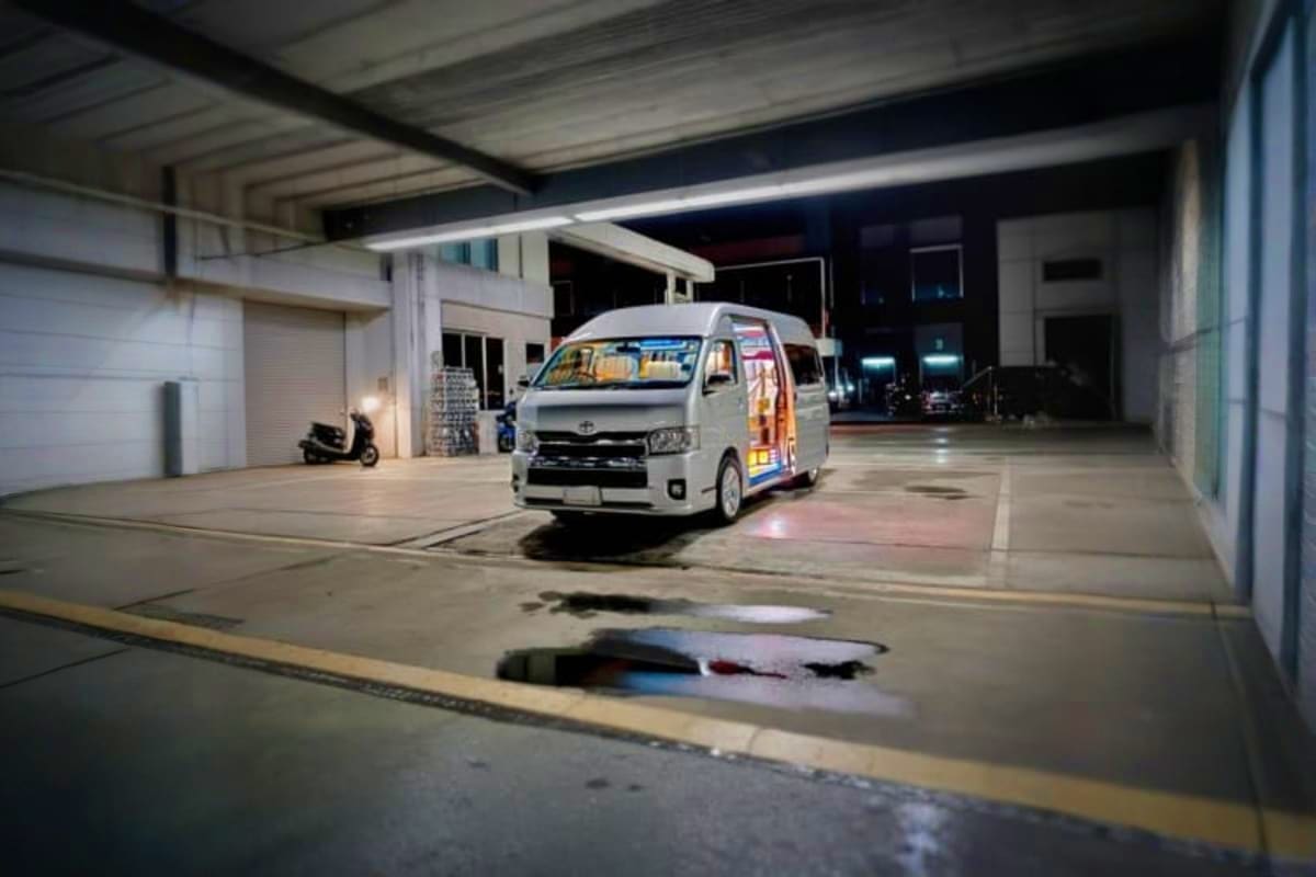 White Toyota van parked in covered garage at night, ready for airport transfer service
