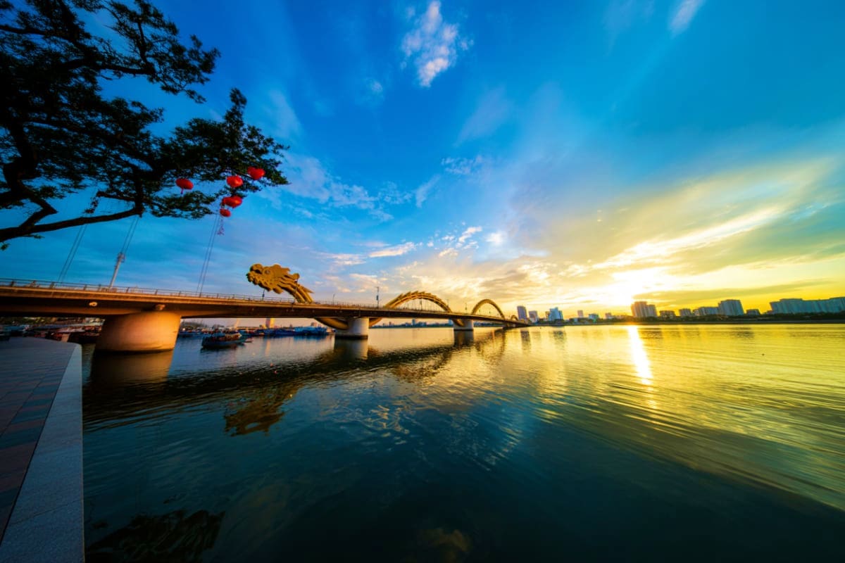 Dragon Bridge in Da Nang at sunset with golden light reflecting on the Han River and city skyline in background