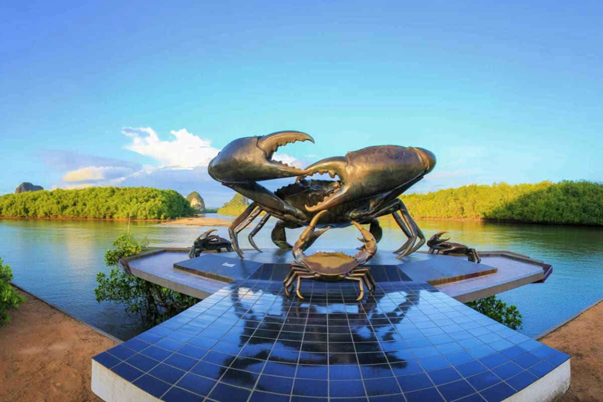 Enroute Krabi city tour to Phuket Large bronze crab sculpture on tiled platform overlooking river with mangrove forests and limestone cliffs in background