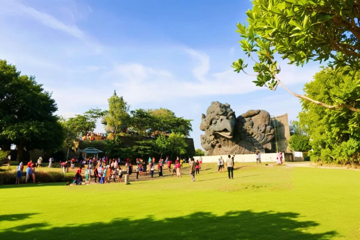 Large stone statue of mythical Garuda and Wisnu figures at GWK cultural park in Bali with visitors on green lawn
