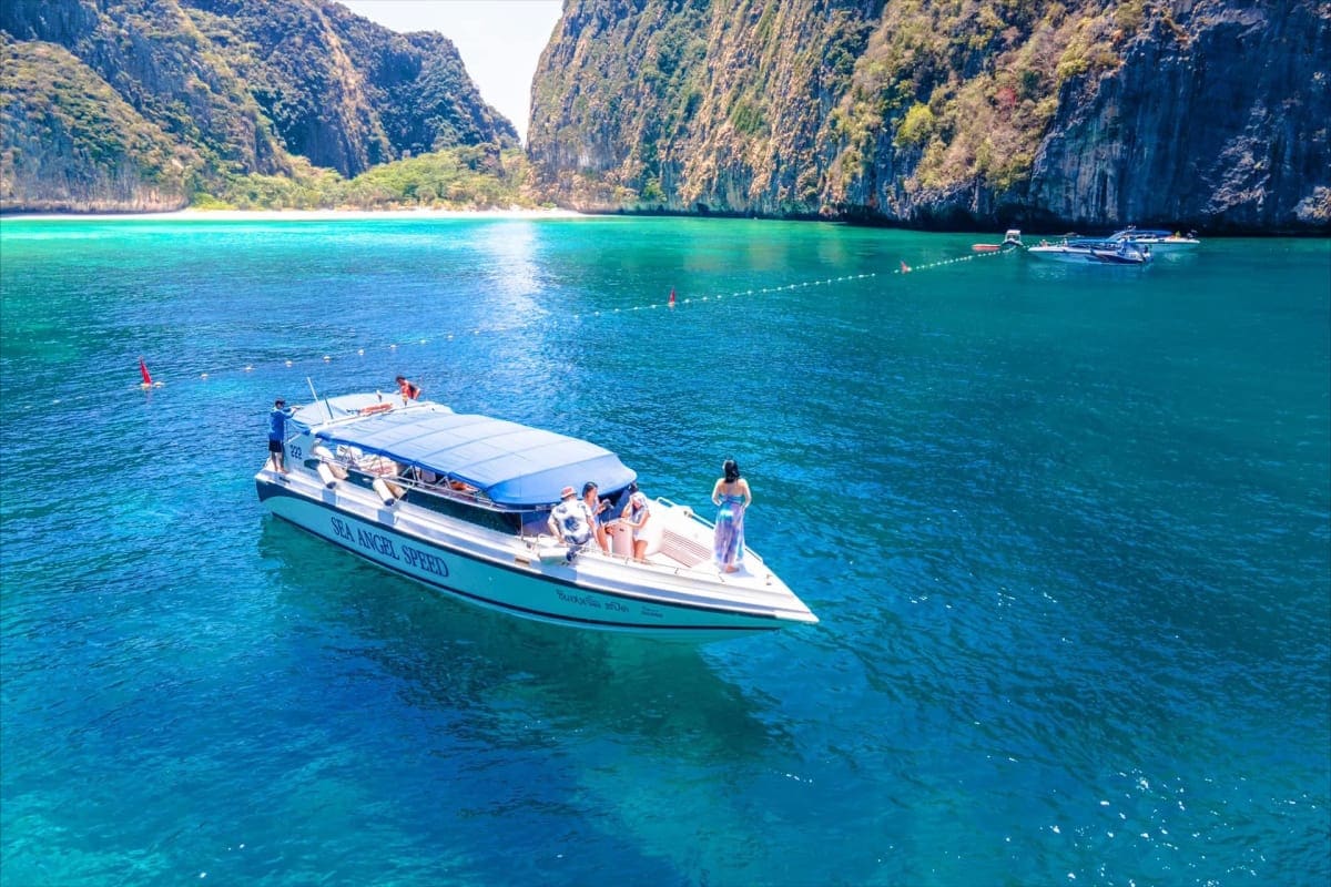 Speedboat moored in turquoise waters with towering limestone cliffs at Hong Island, Thailand