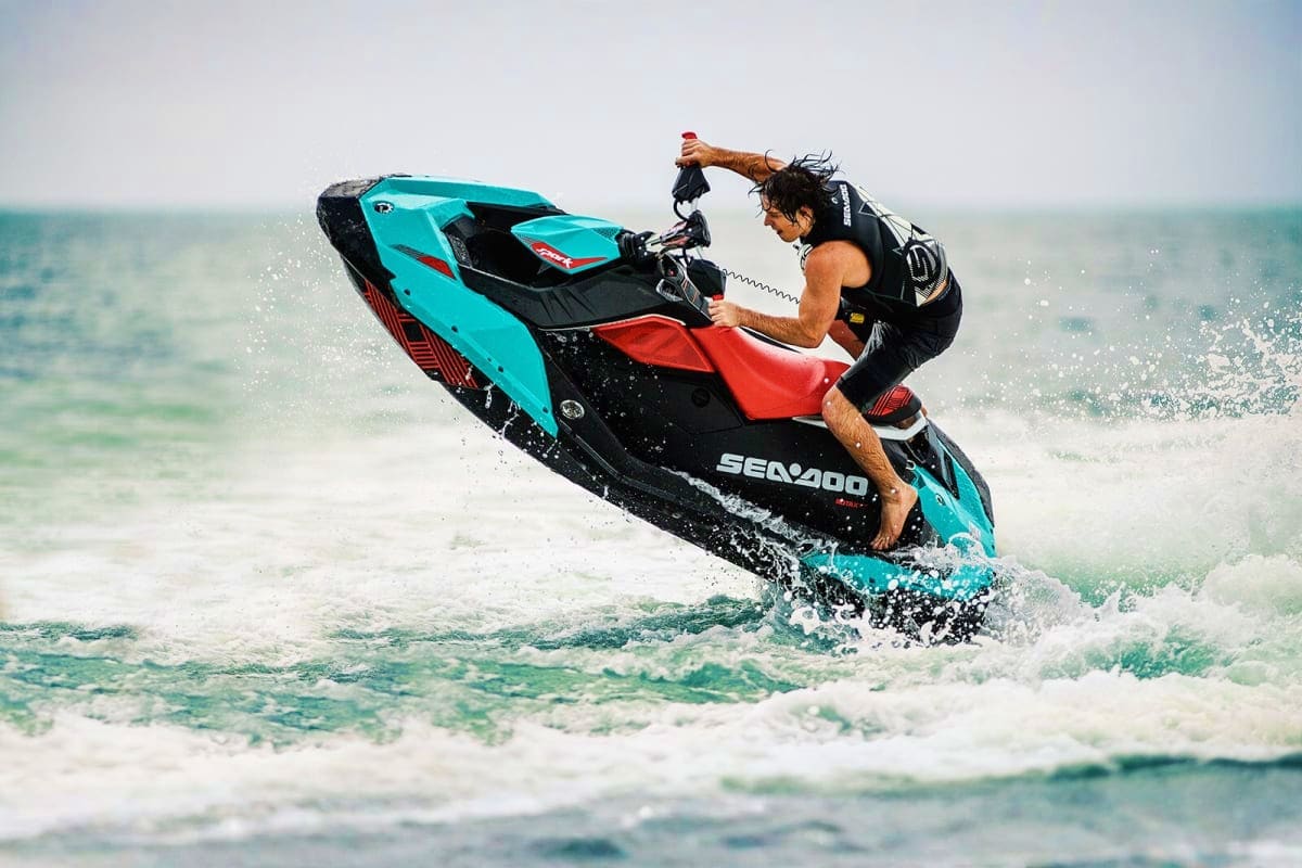 Man riding a turquoise and black Sea-Doo jet ski through ocean waves in Abu Dhabi waters